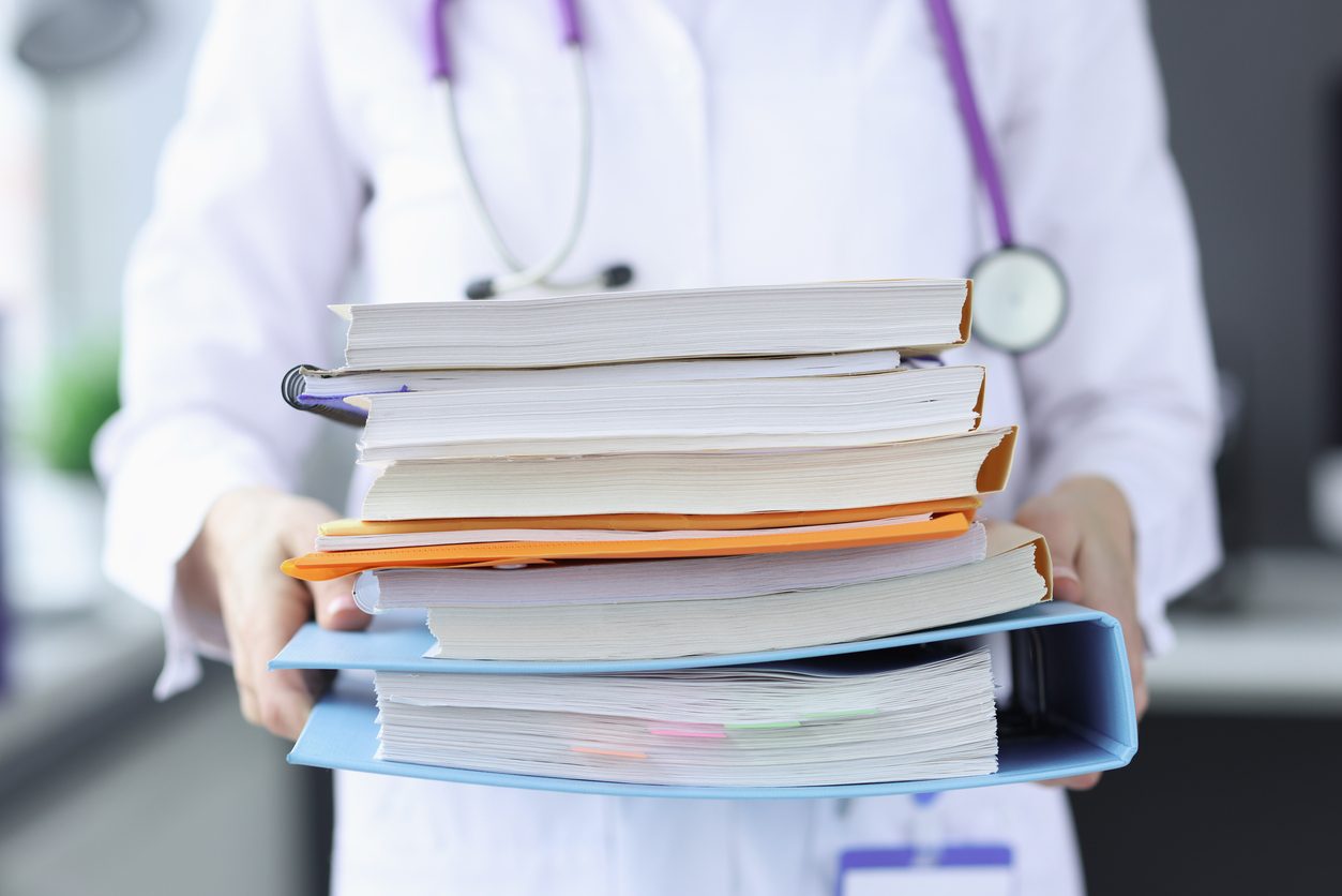 Doctor is holding large stack of folders. Evidence-Based Treatment concept image