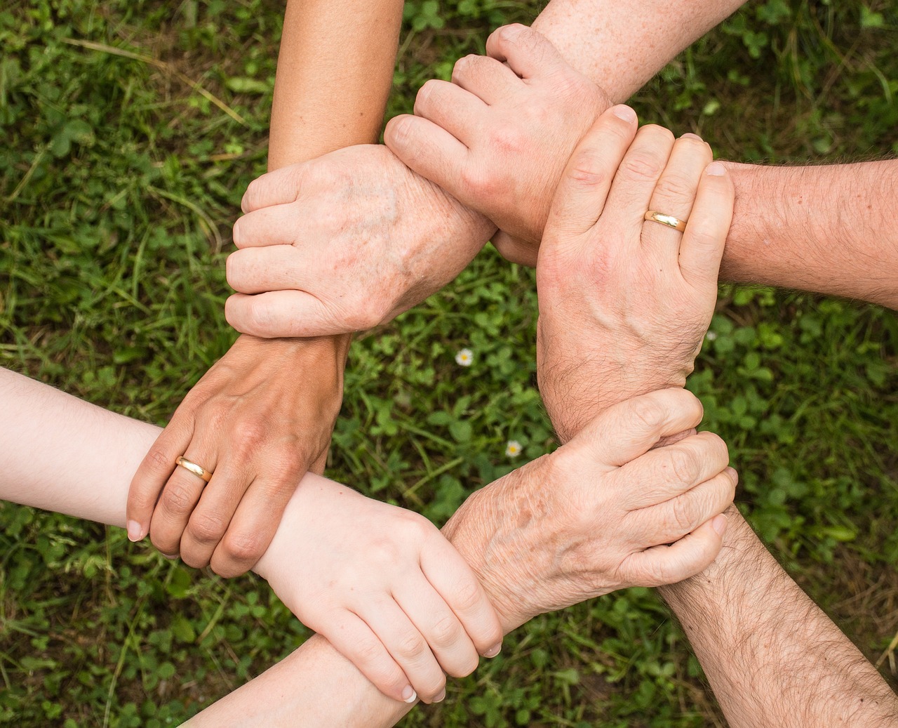 6 Hands connected by the wrist in a symbolic support group for addiction