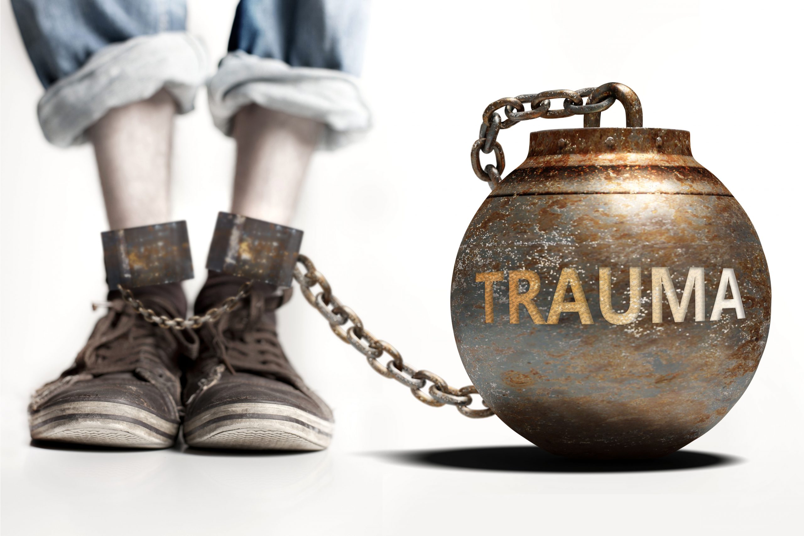 Iron Ball and chain on mans ankle with the word "Trauma" engraved on ball - Trauma and addiction concept images